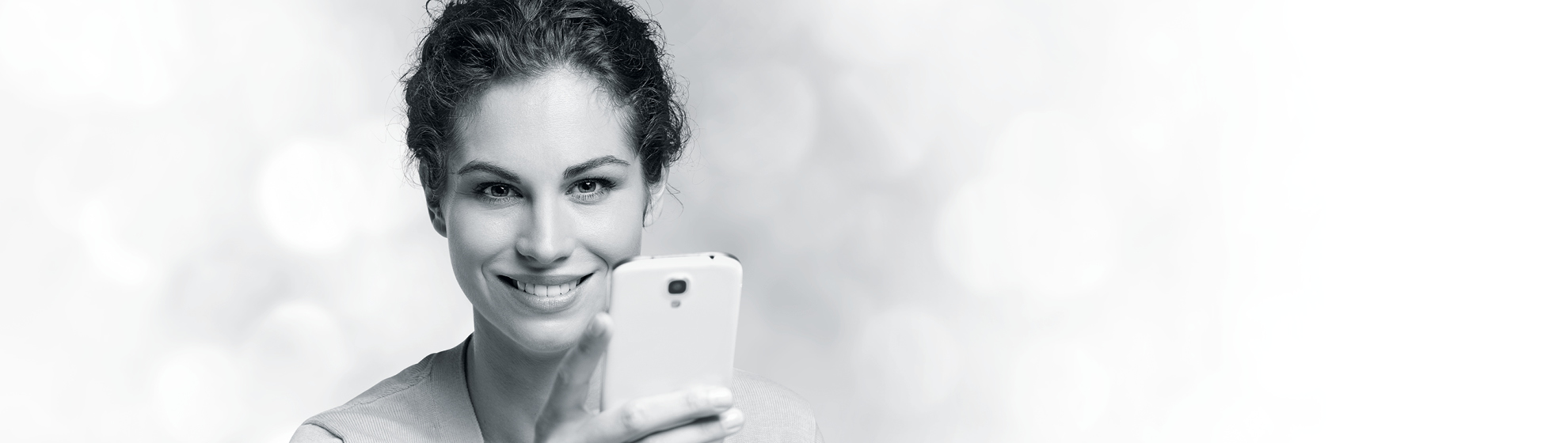 Eine lächelnde Frau mit einem Smartphone in der Hand.